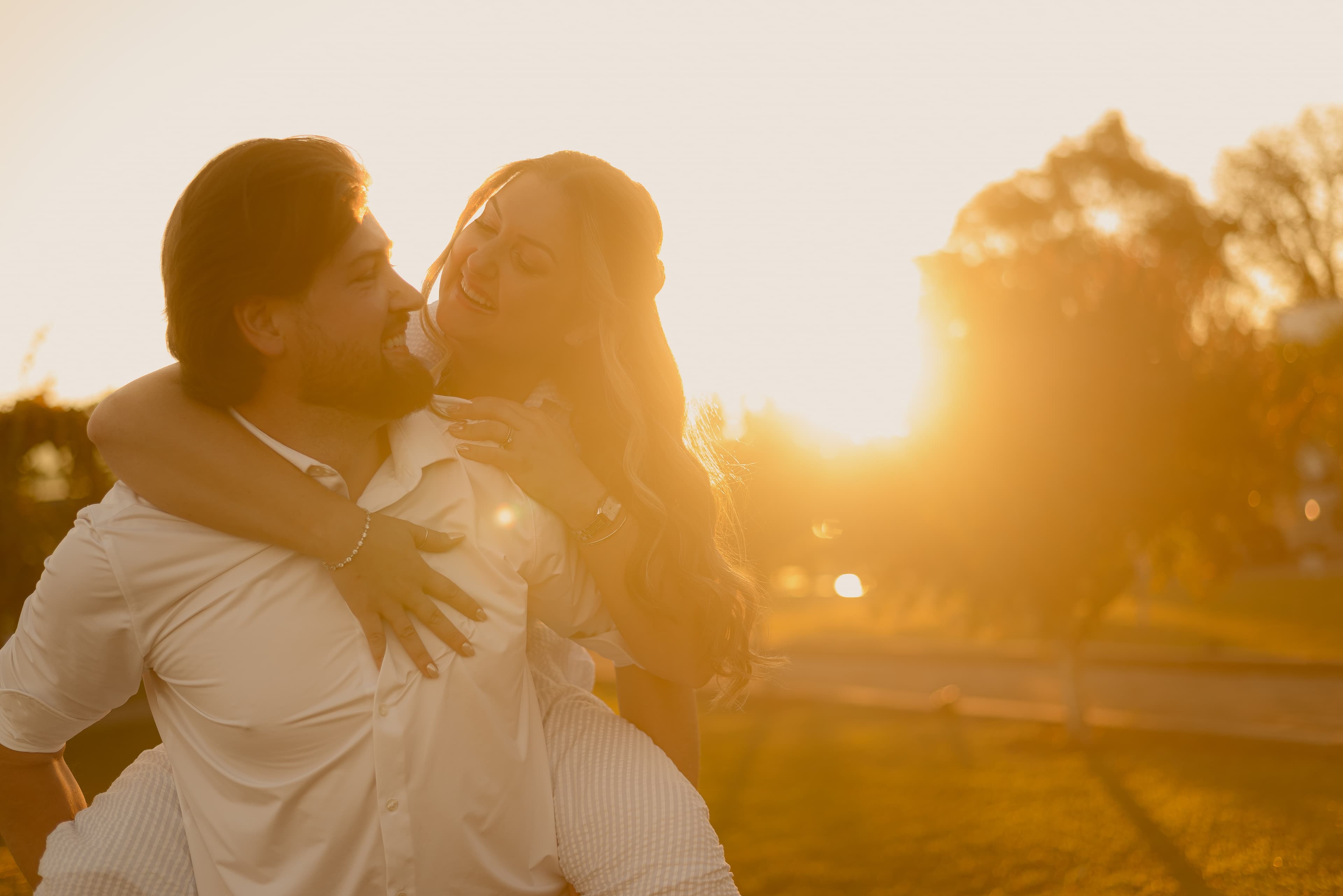 Poliana e Patrick sorrindo em um campo ao entardecer